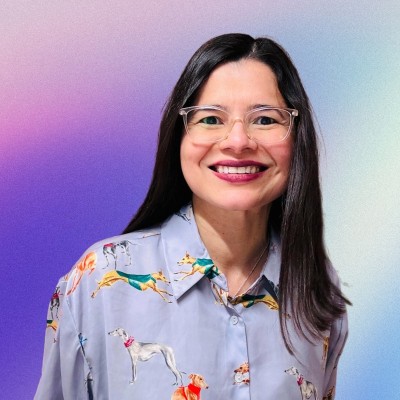 Aleyda Solis smiles wearing glasses and a dog-patterned shirt against a colorful gradient background.